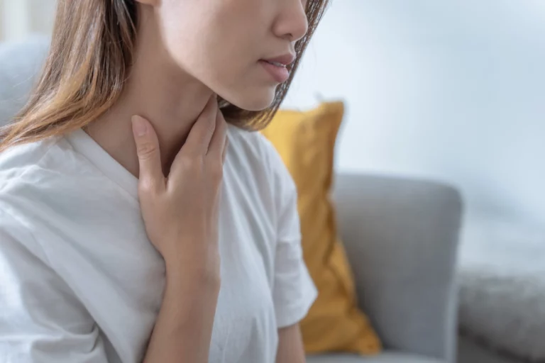 woman touching her neck to check her thyroid